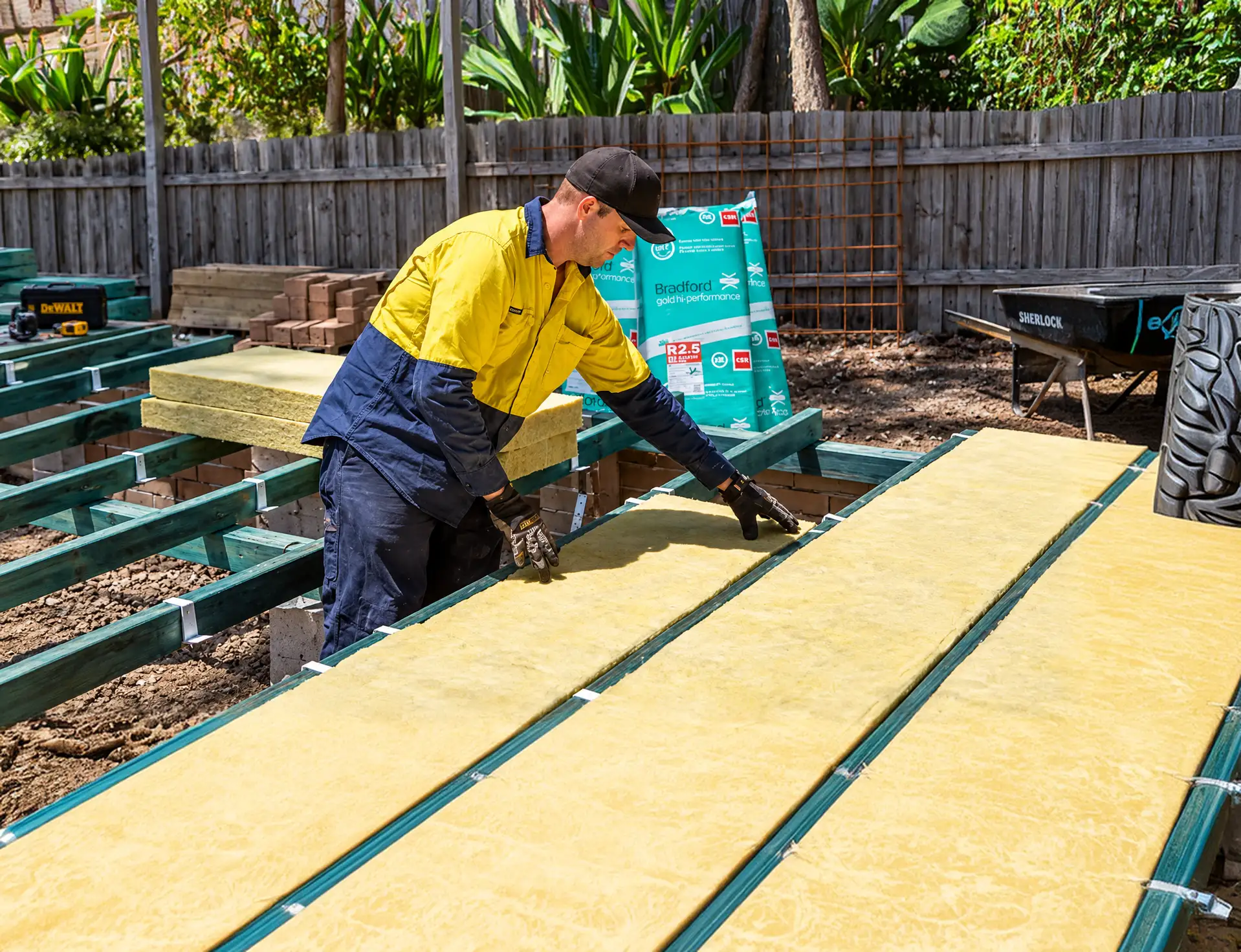 House Insulation Canberra installer laying insulation batts on a deck outside a home