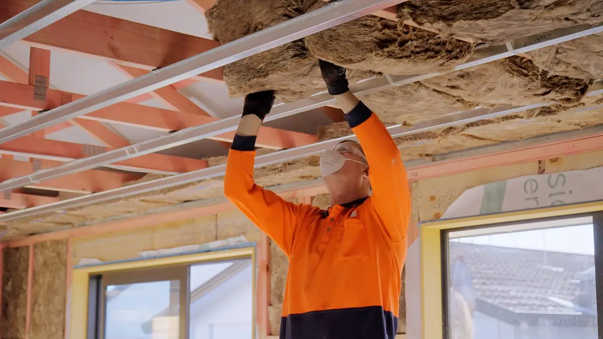 Installer fitting ceiling panels in a new build