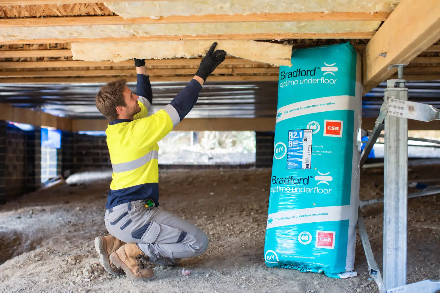 Installer fitting underfloor insulation between floor joists
