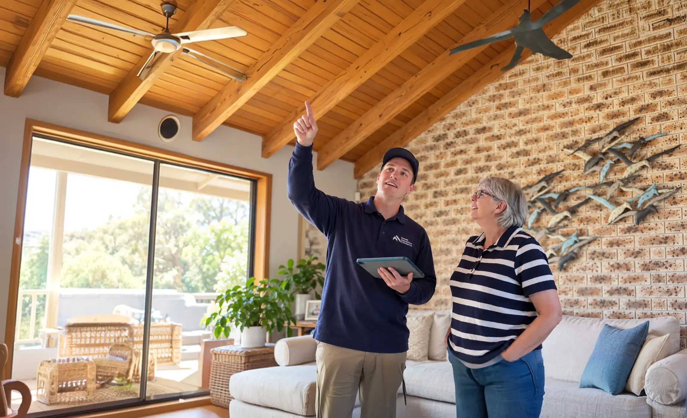 House Insulation Canberra installer pointing out the ceiling to a homeowner in her living room