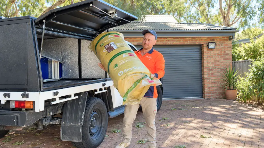 House Insulation Canberra installer carrying a roll of ceiling batts from the ute