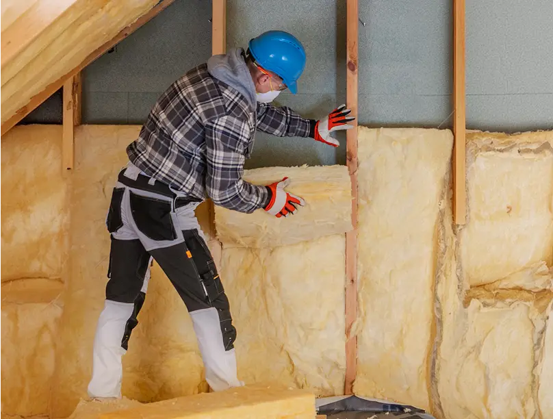 Installer fitting wall insulation batts into an open wall frame