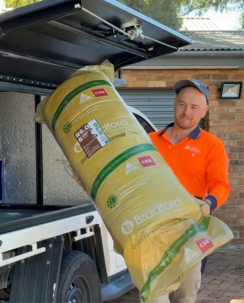 Installer carrying a roll of insulation into a Canberra home