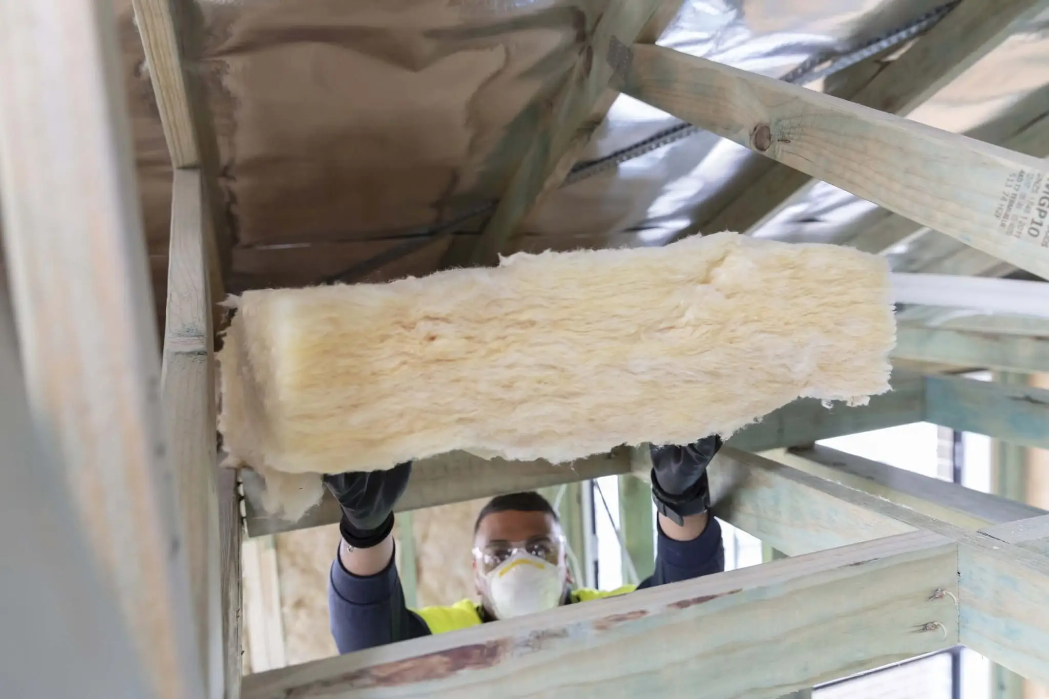 Installer passing an insulation batt up into a ceiling space